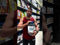 Man holding Beef Mass Gainer 3.13kg by Applied Nutrition in a supplement store aisle. Features 42g beef protein isolate per serving for muscle gain.